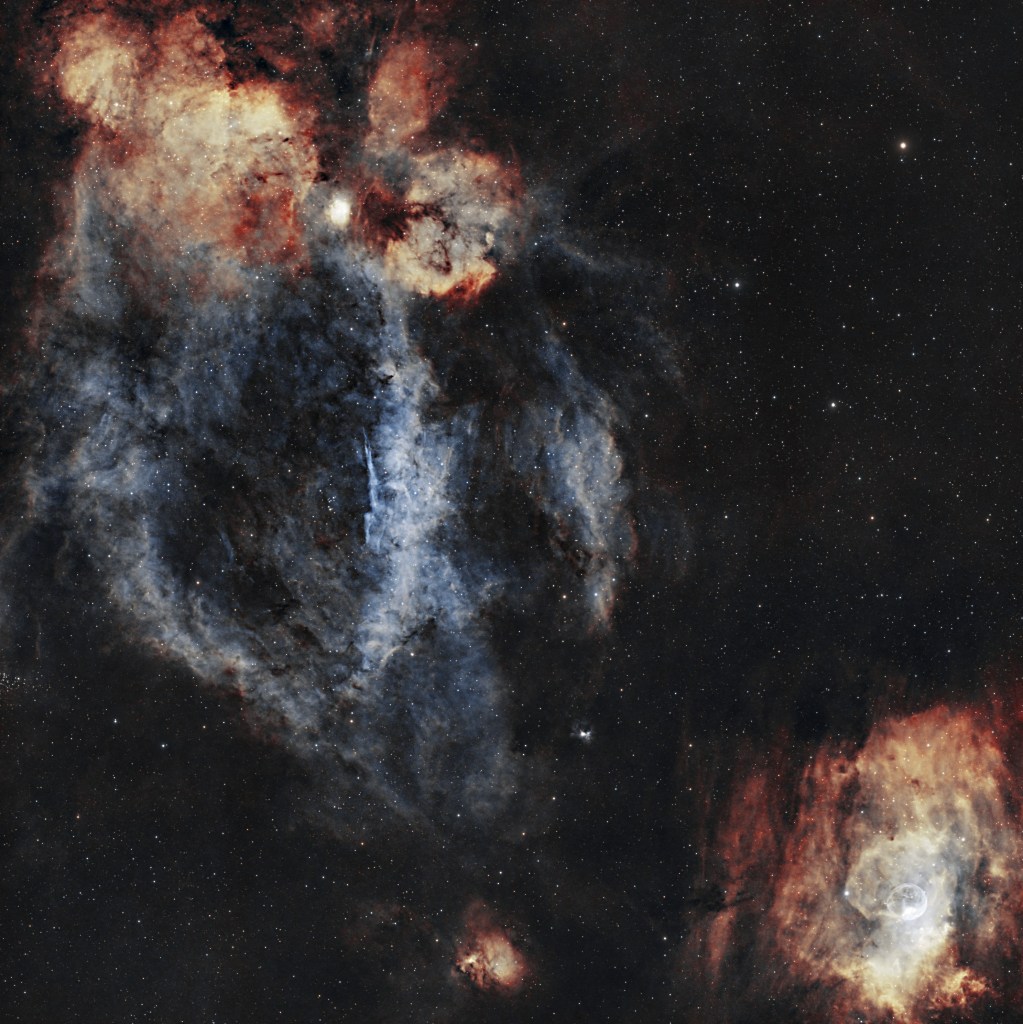 Astrophotography of the Lobster Claw and Bubble Nebulae in a single frame, showcasing glowing hydrogen clouds and a bright circular bubble.